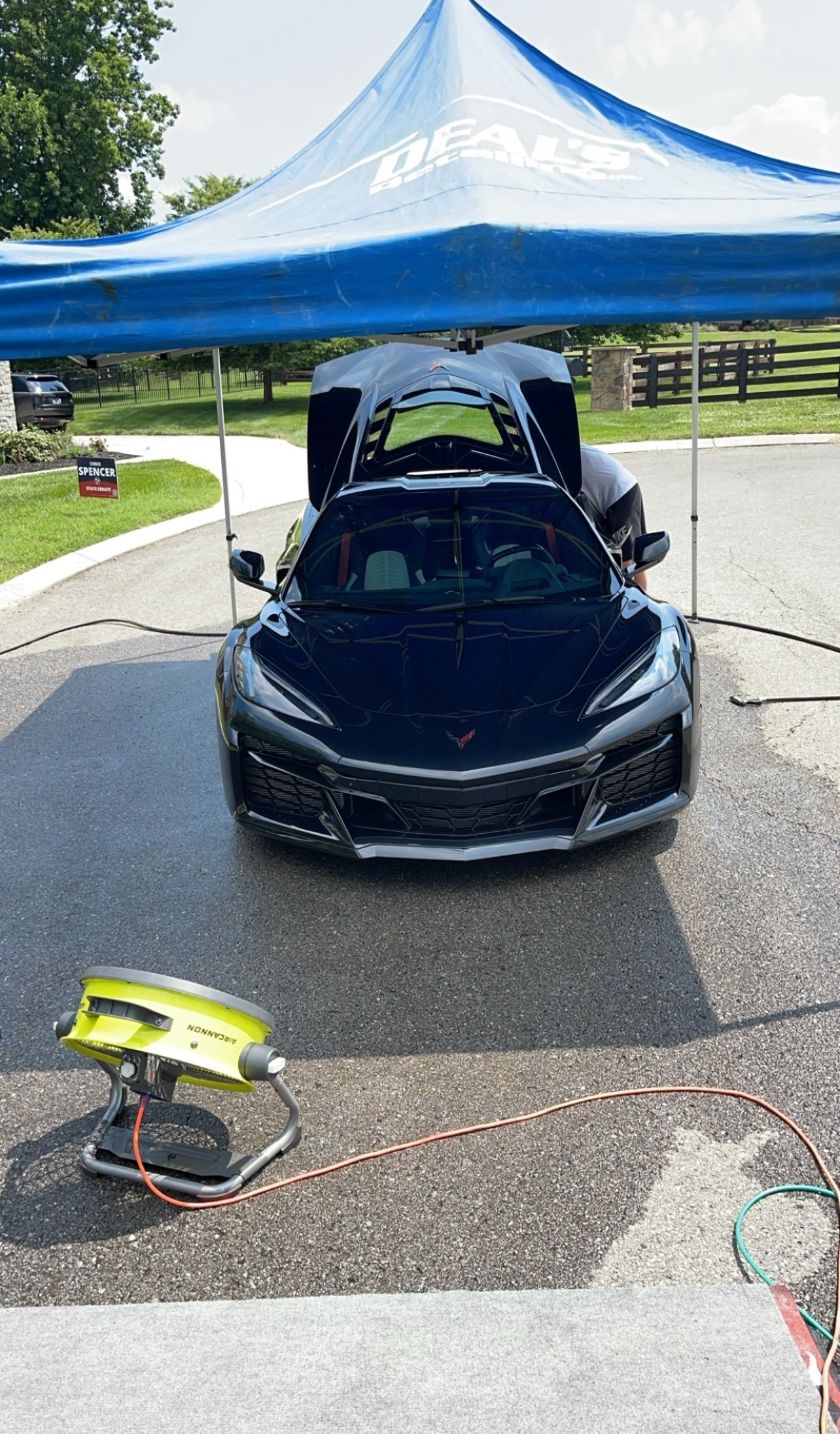 A man is polishing a black car with a yellow sponge.