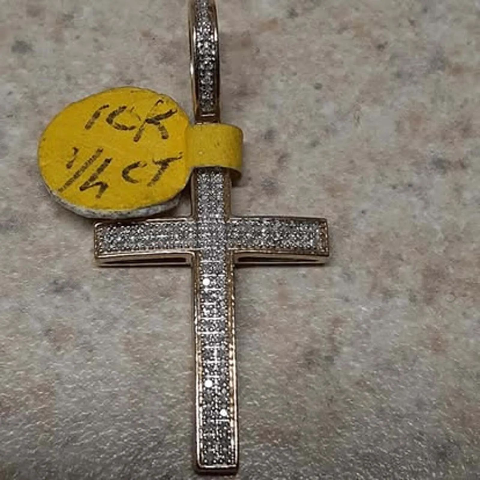 A cross pendant with a yellow tag that says tck 1/4 ct