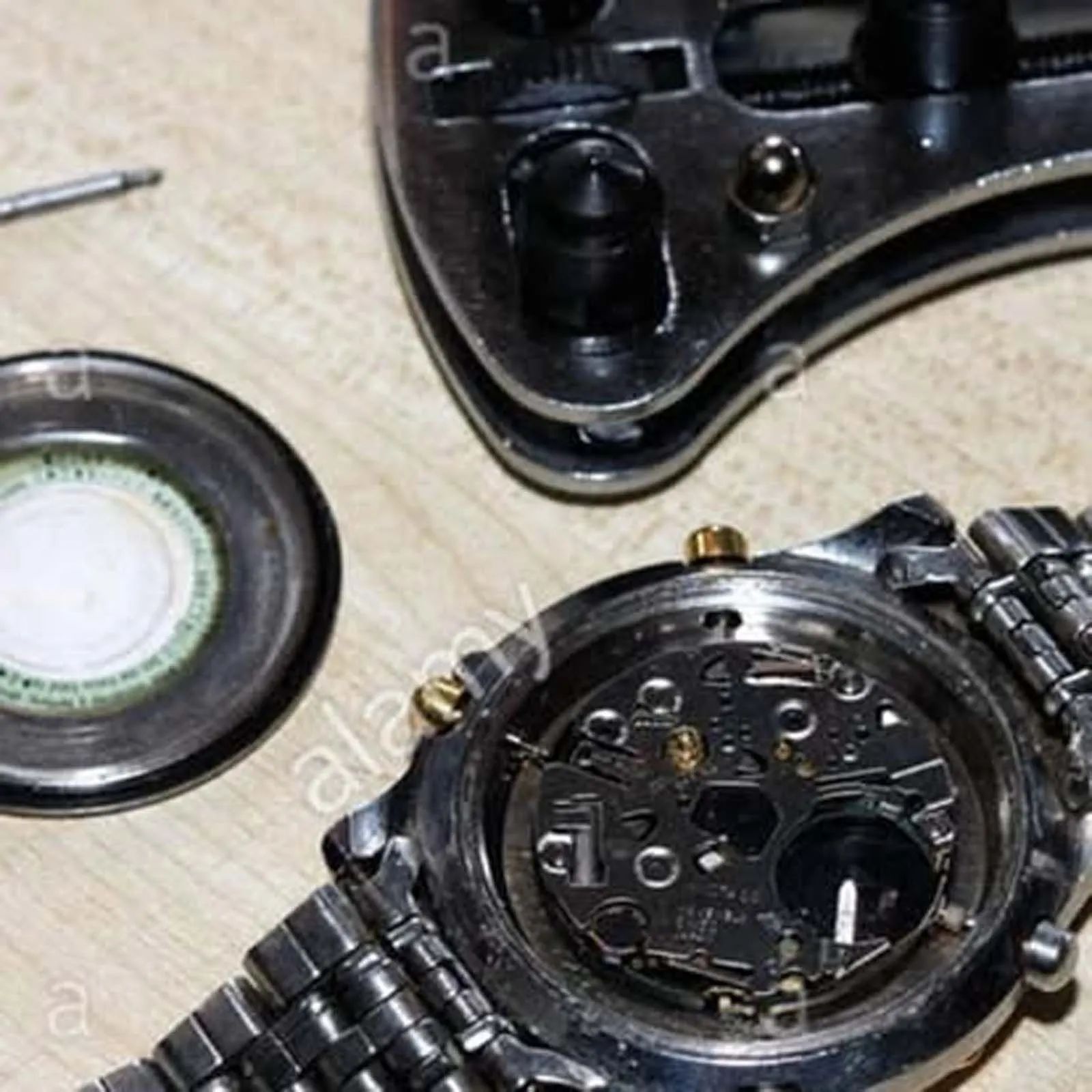 A watch is being repaired on a wooden table