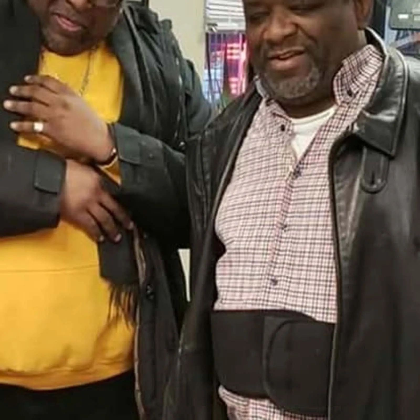 Two men are standing next to each other and one of them is wearing a black jacket.