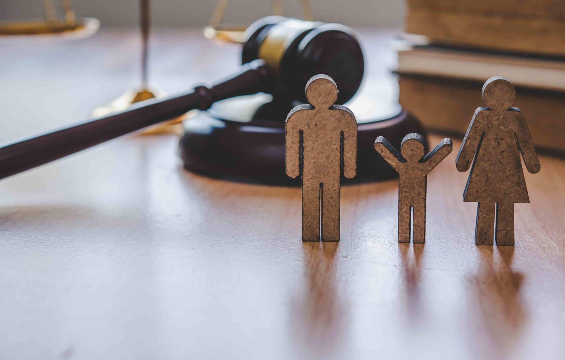 Court gavel behind three wooden family figures on a desk