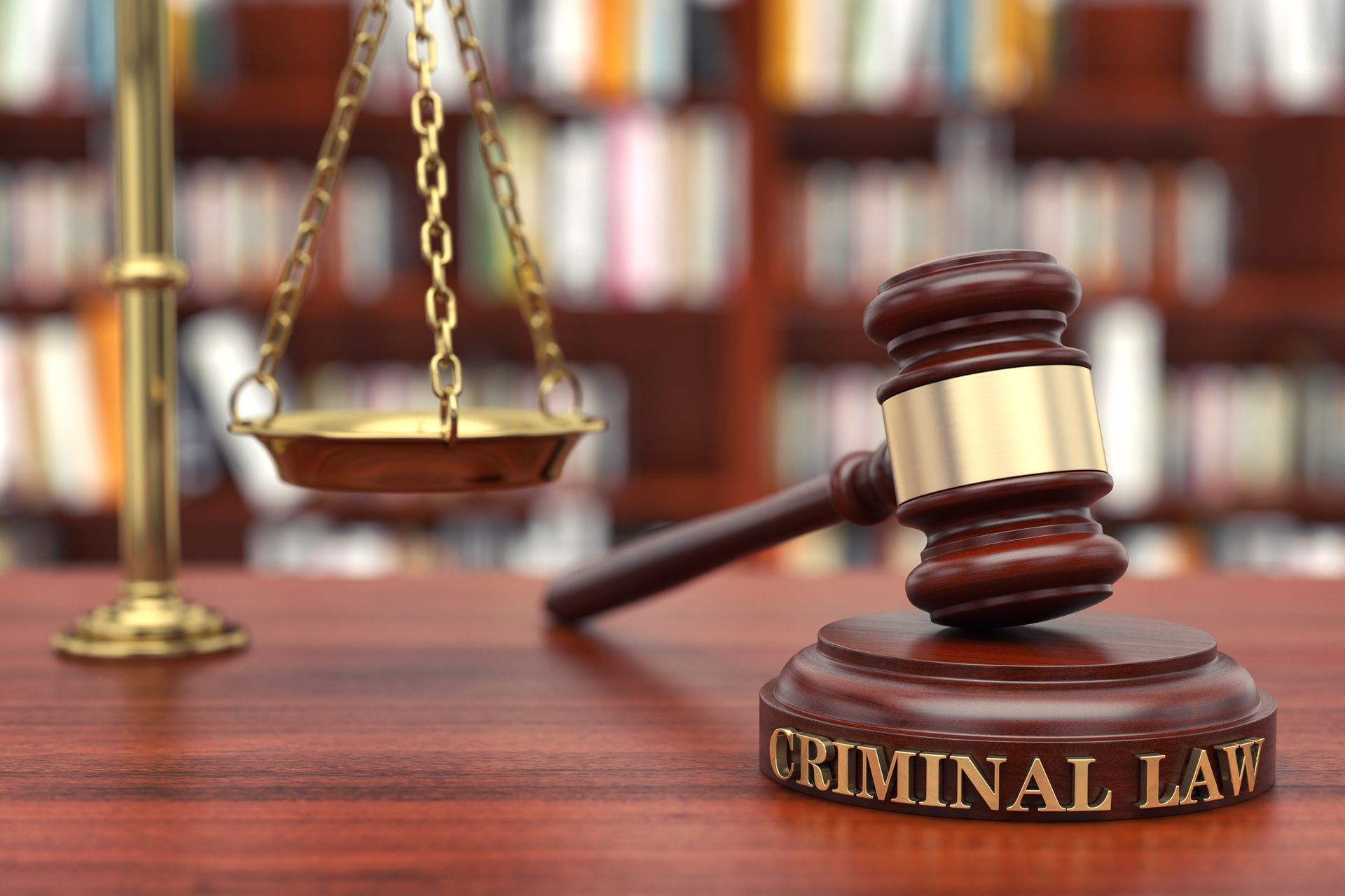 Gavel, scales, and law books on a desk with “CRIMINAL LAW” visible in a courtroom setting
