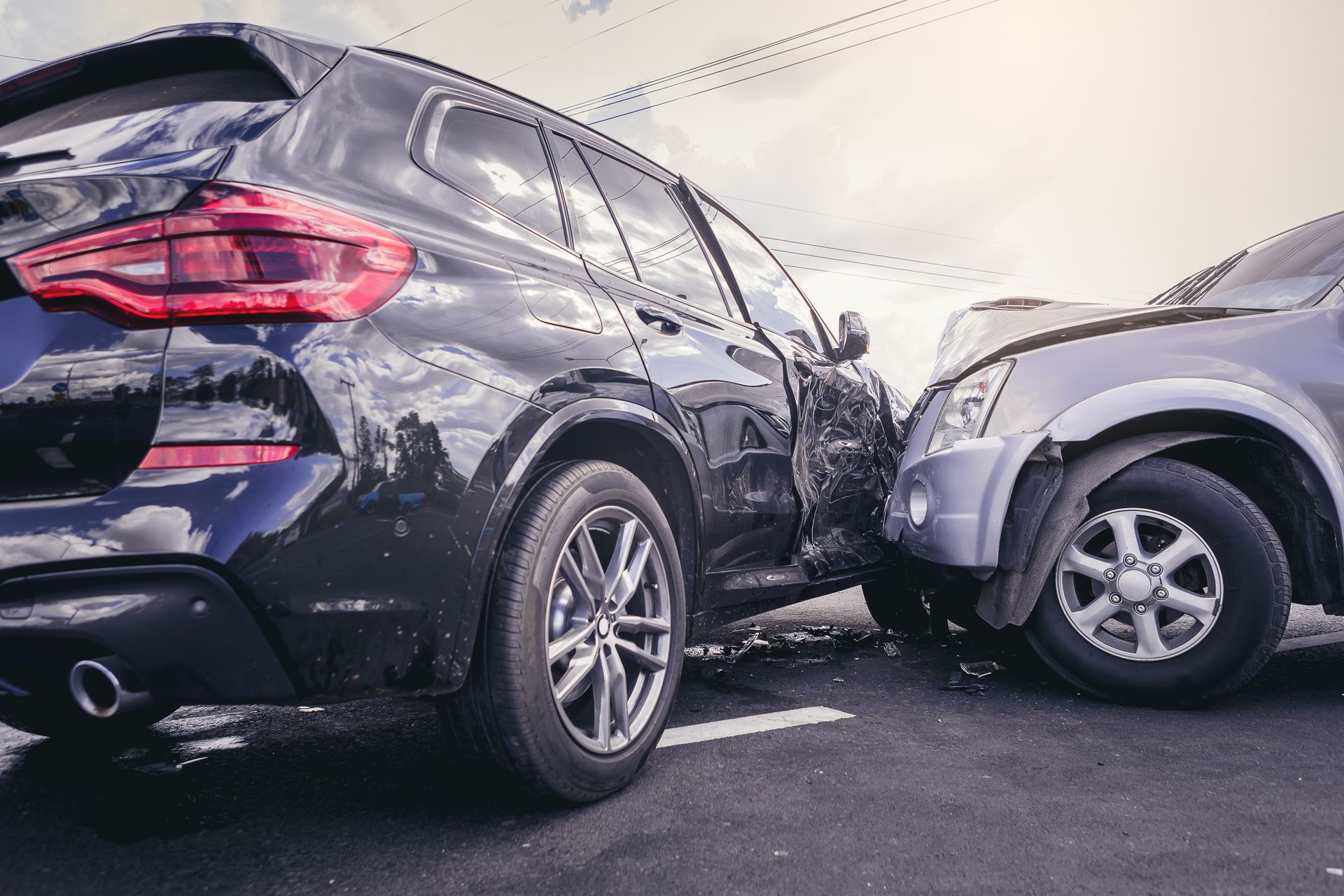 Black SUV and silver car after a front-end collision on a wet roadway