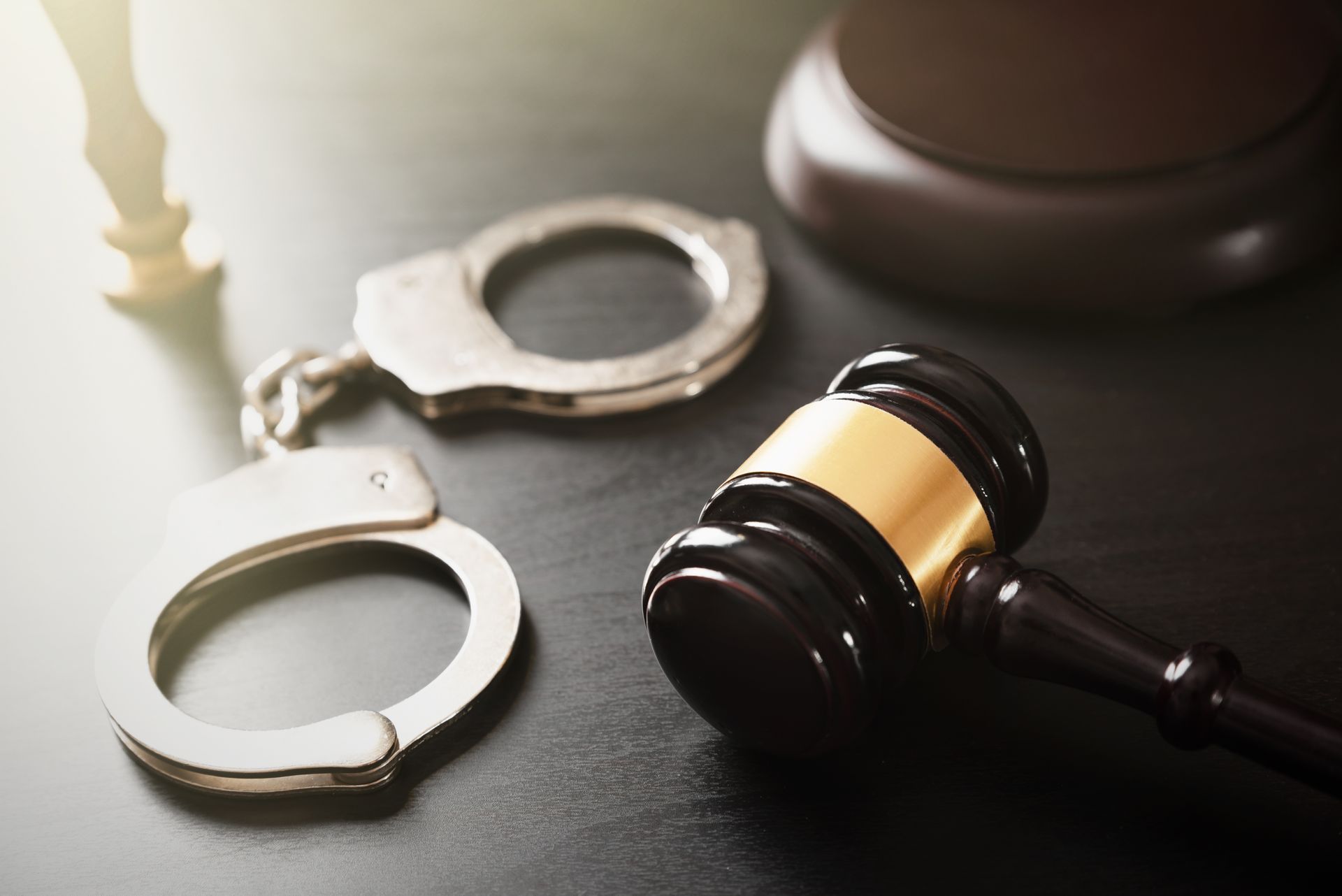 Handcuffs and a judge’s gavel on a desk, suggesting a legal arrest or court case