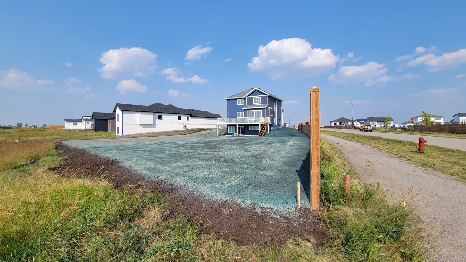 New construction home in field, partially covered in green netting, under a blue sky.