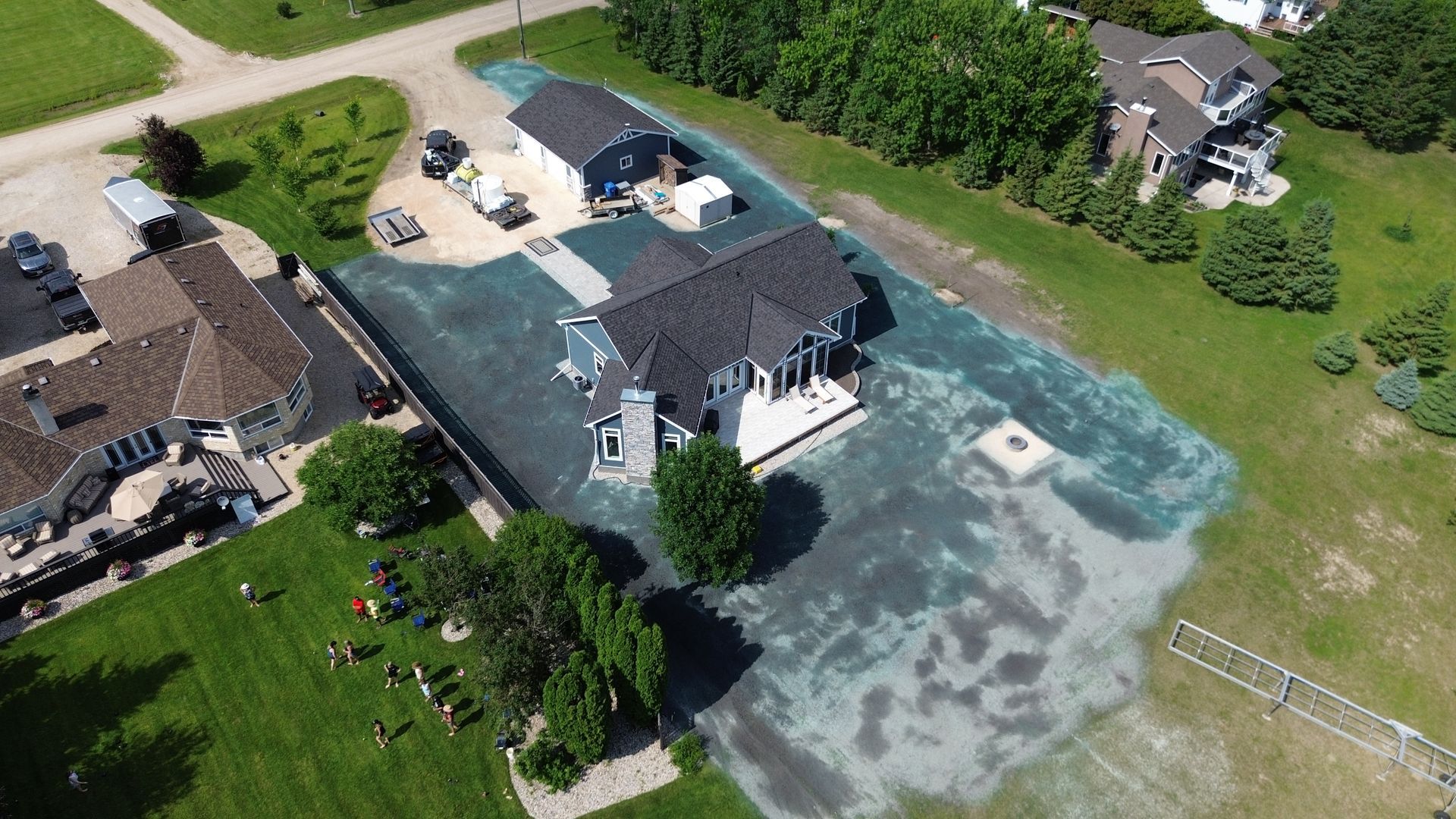 Aerial view of a house with newly seeded lawn. Green and blue-green hues dominate the yard.