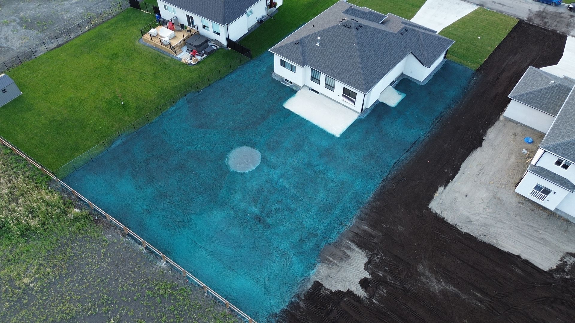 Aerial view of a house with a newly seeded yard; grass is blue-green, surrounded by newly turned dark brown soil.