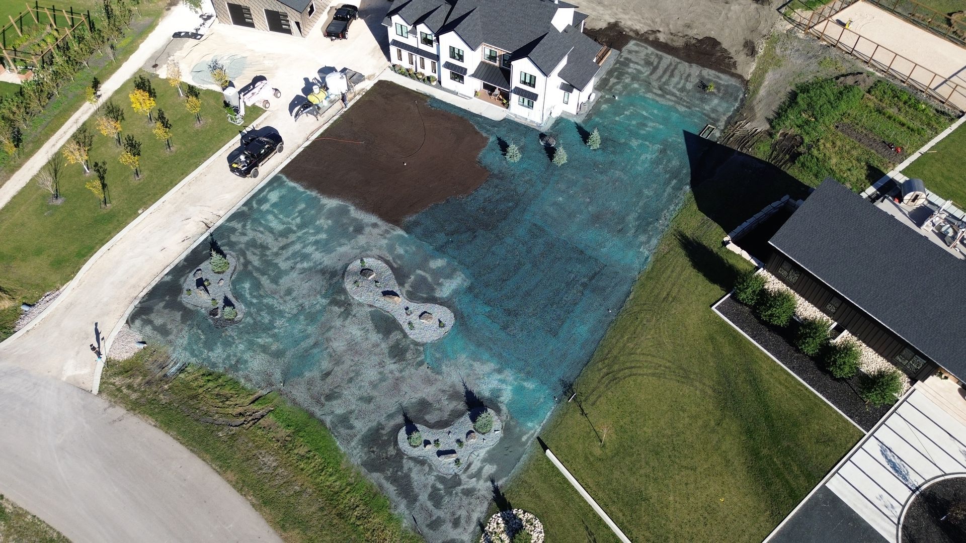 Aerial view of a flooded construction site, with a house, and areas of blue and brown water covering the land.