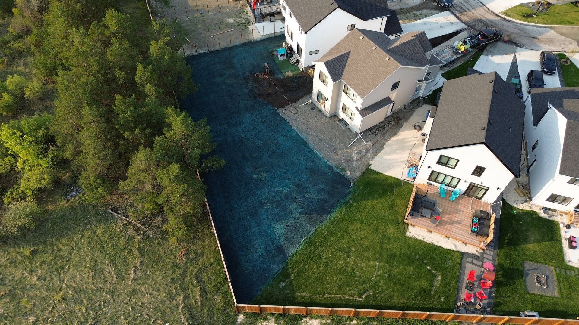 Aerial view of residential homes with manicured lawns and a patch of newly planted grass, possibly sod.