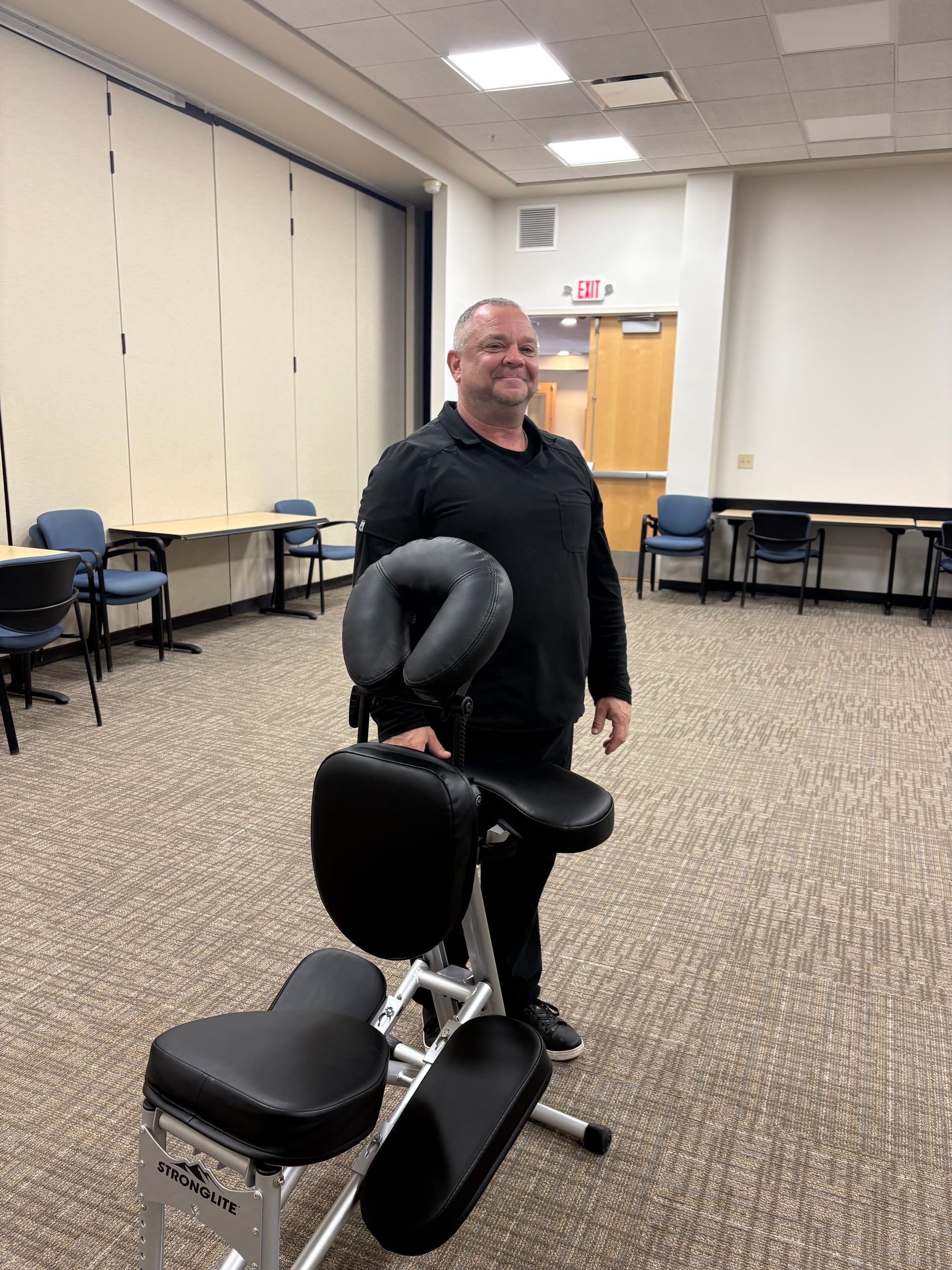 Two massage therapists giving a back massage in a brightly lit room.