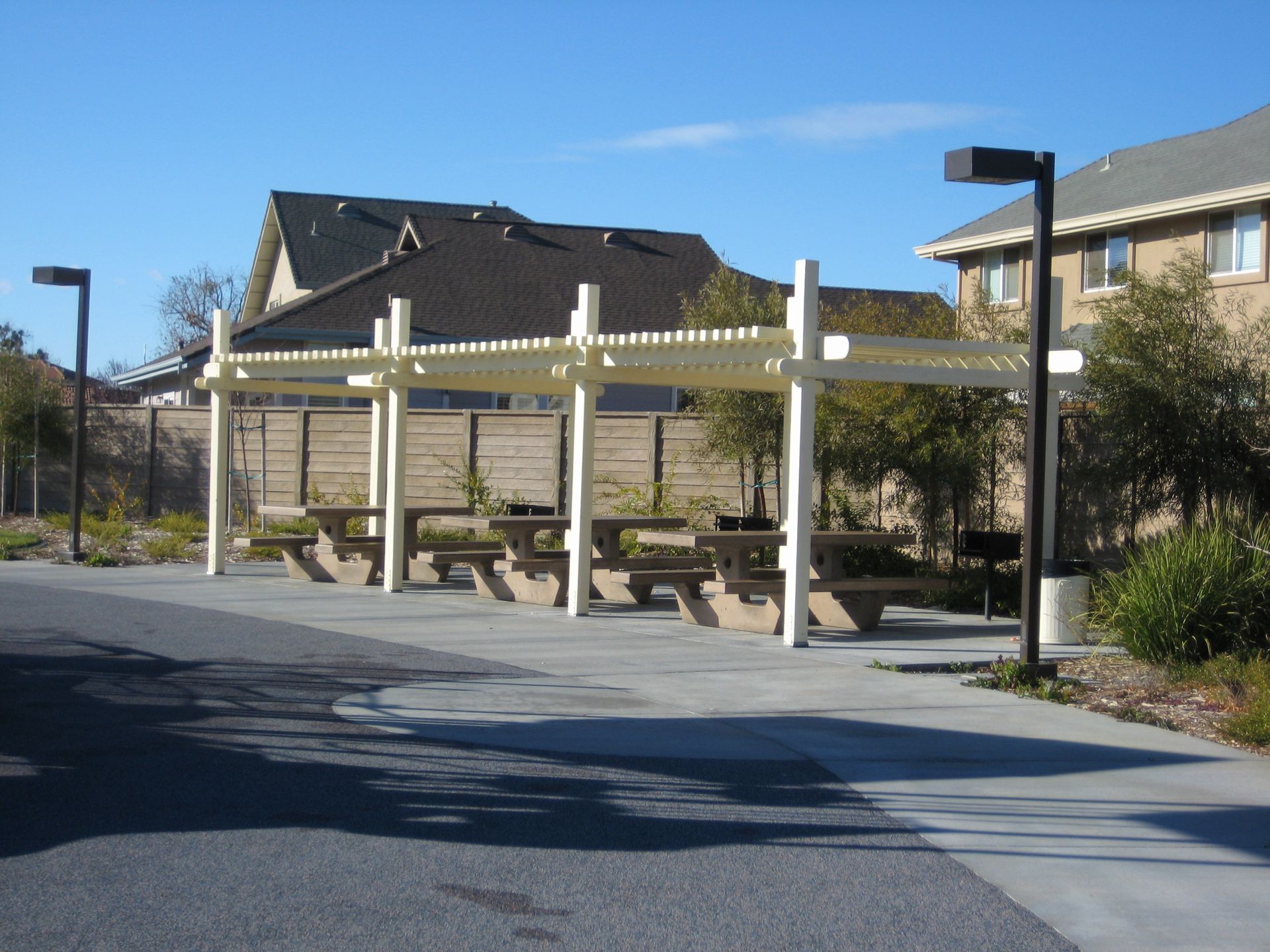 a row of picnic tables under a pergola in front of a house