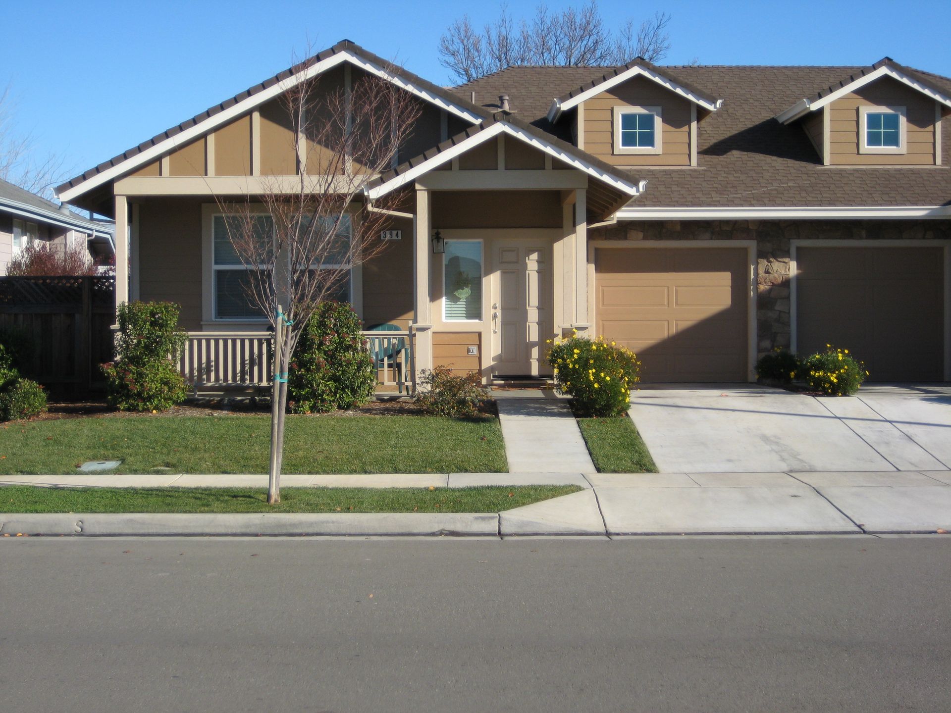 a house with two garages and a porch on a sunny day