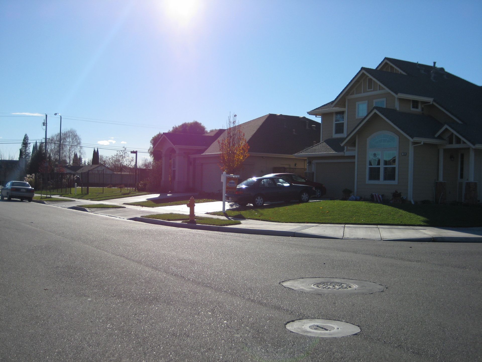 a row of houses on a sunny day with a black car parked in front of one of them