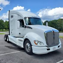 White semi-truck parked outdoors on a paved lot under a partly cloudy sky