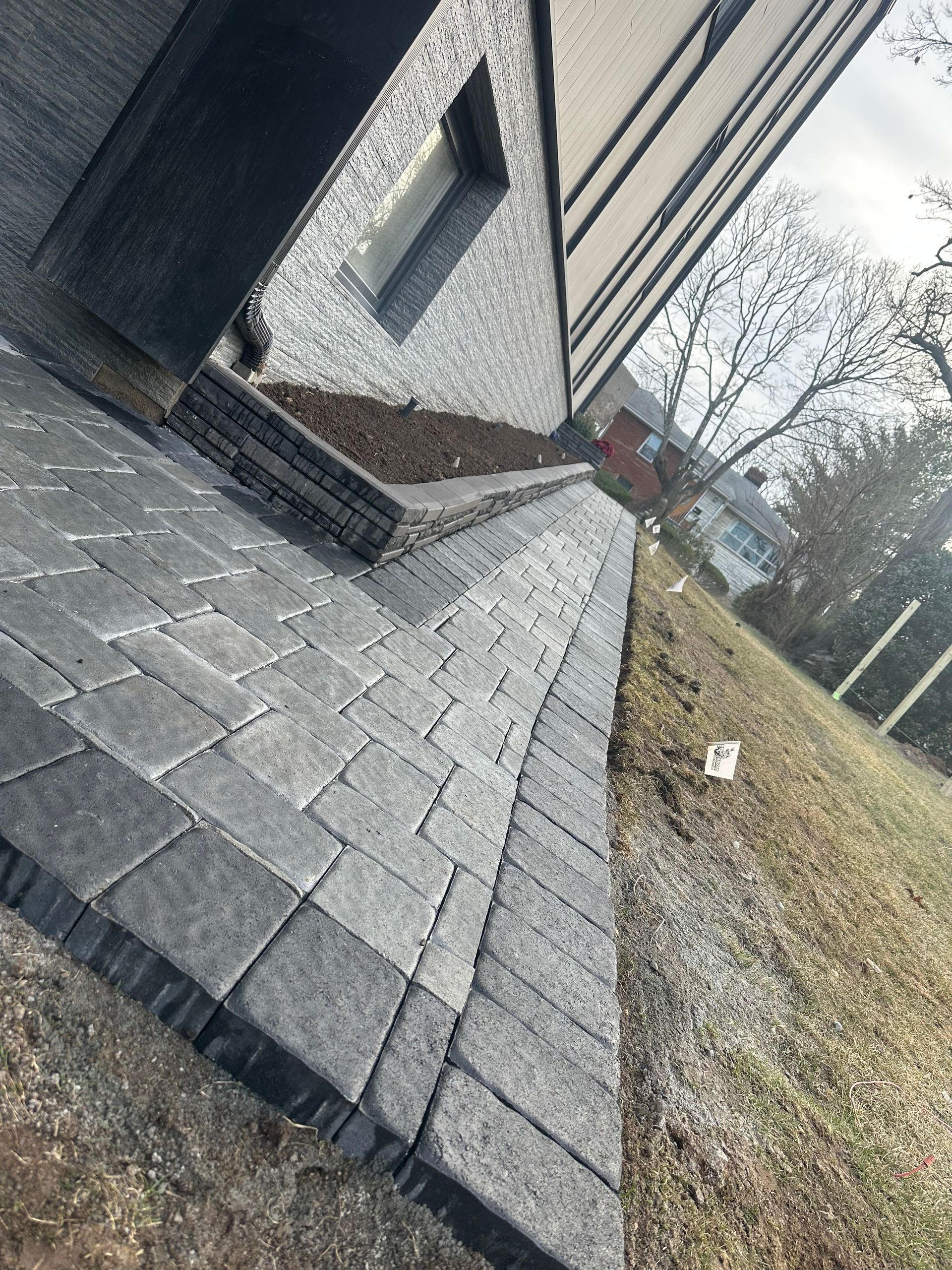 Tilted view of a house exterior with gray shingle roofing, beige siding, and a grassy yard.