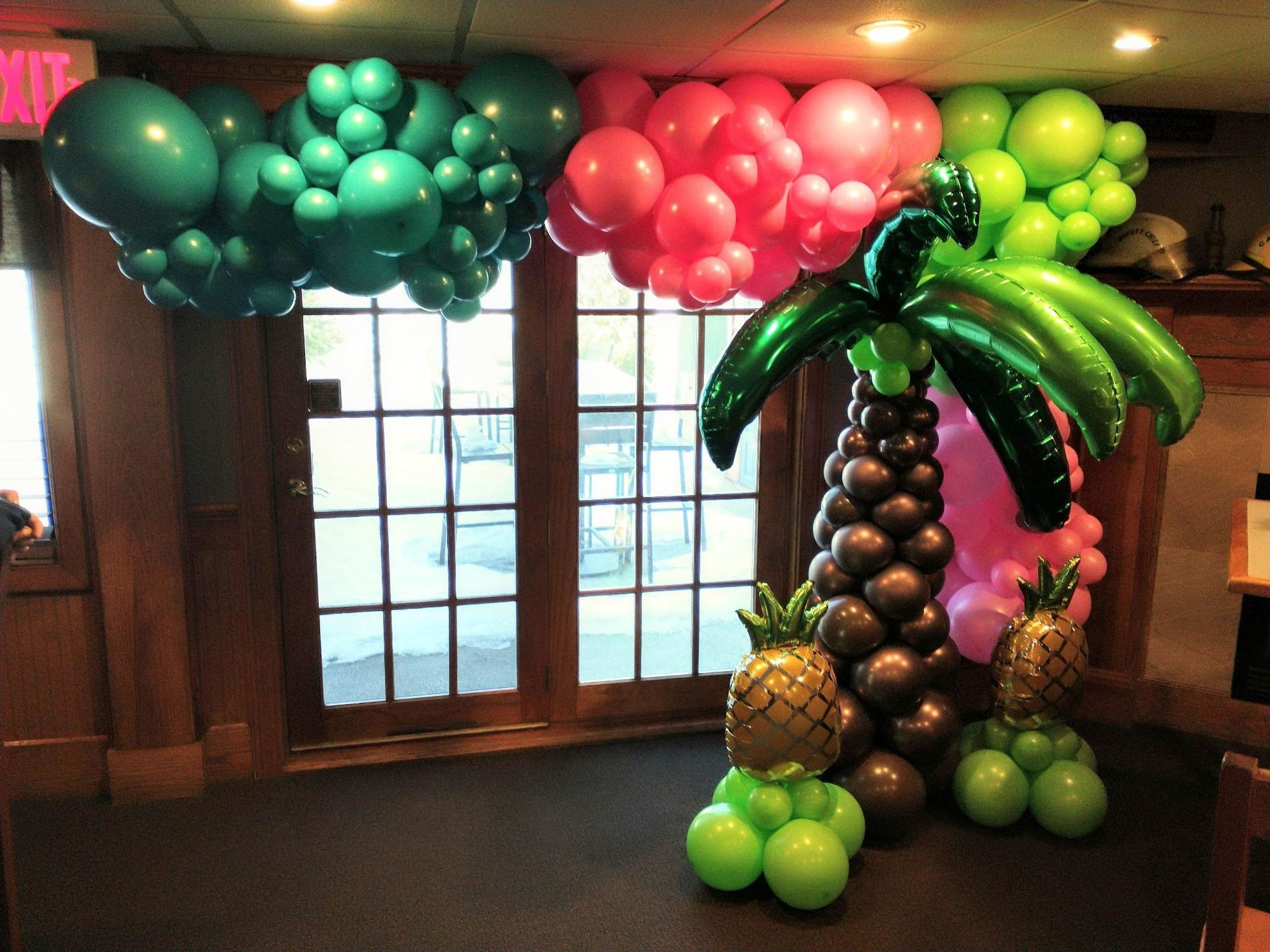 A room decorated with balloons in the shape of palm trees and pineapples