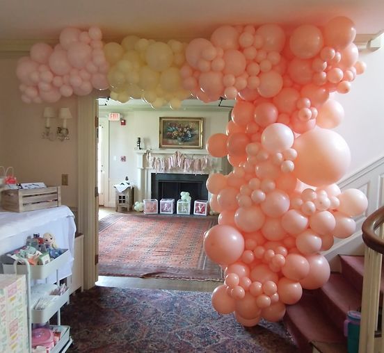 A bunch of pink balloons are hanging from the ceiling in a room.
