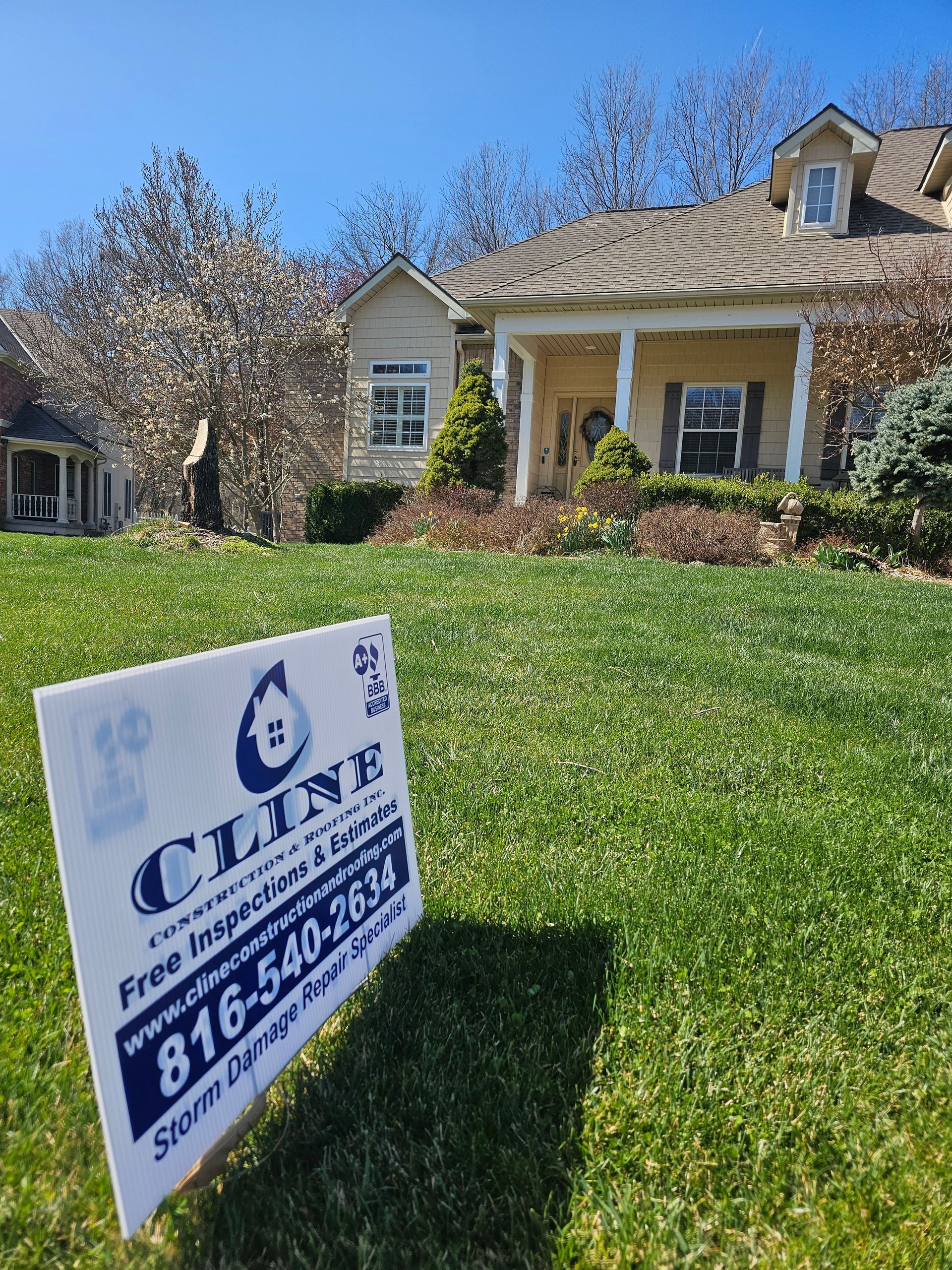 Lawn sign for a home service company on a green front yard, with a house and trees in the background