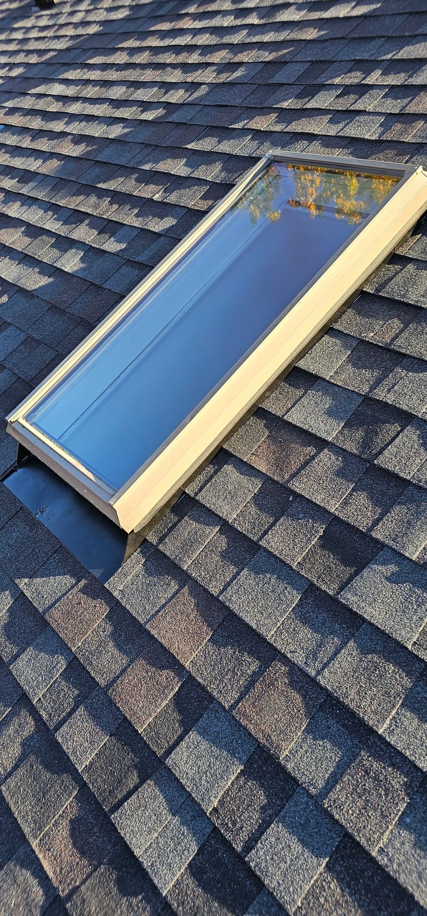Blue skylight window on a gray shingled roof