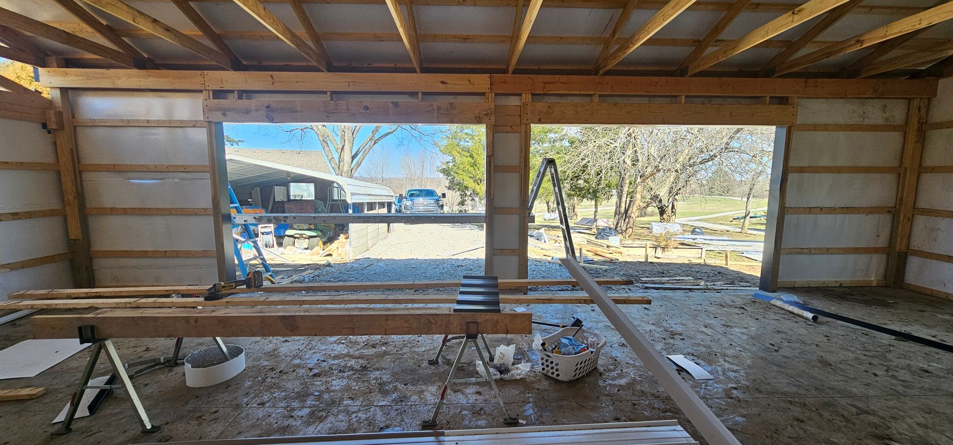 Interior of unfinished wooden shed with open doorway, workbench, and construction materials on the floor