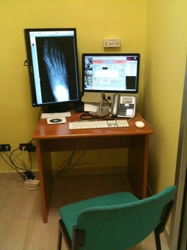 Scrivania con due monitor, tastiera, mouse e sedia in una stanza gialla.