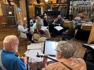 People seated in a cozy pub, playing a live music session with instruments and sheet music