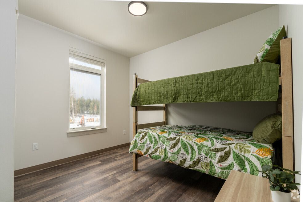 A bedroom with a bunk bed and a window.