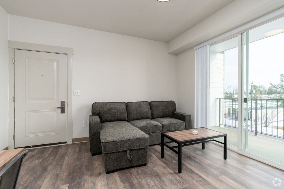 A living room with a couch , coffee table , and sliding glass doors.