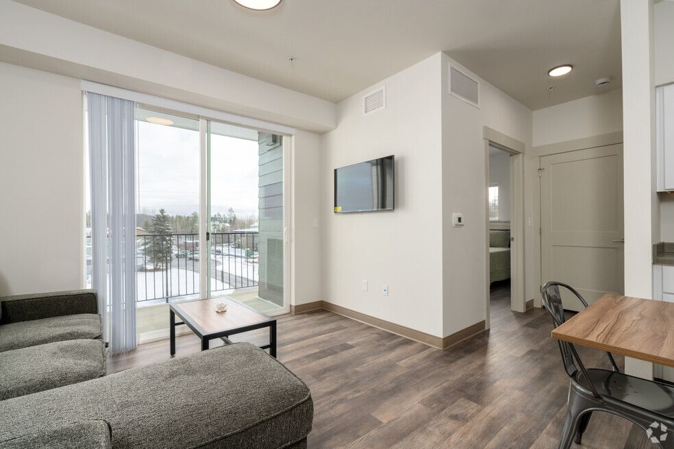 A living room with a couch , table , chairs and a flat screen tv.