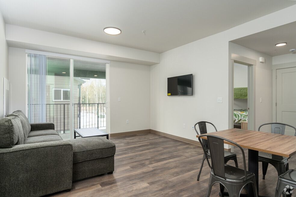 A living room with a couch , table , chairs and a flat screen tv.