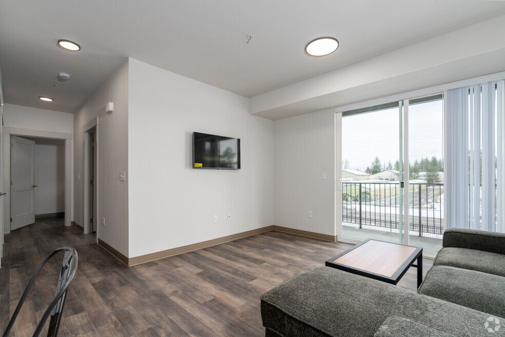 A living room with a couch , television , and sliding glass doors.