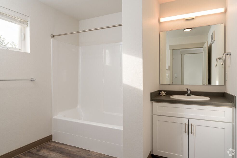 A bathroom with a sink , tub and mirror.