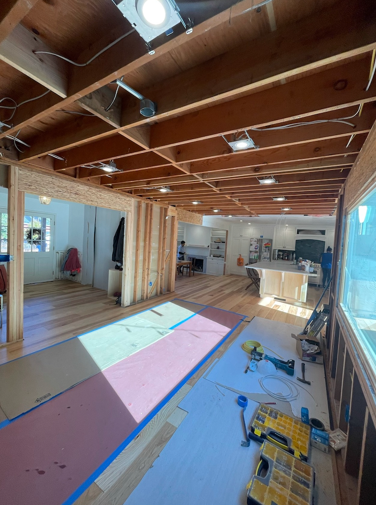 Two construction workers are working on a ladder in a room.