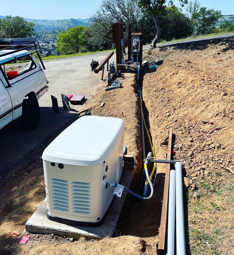A generator on a trailer is parked in front of a building.