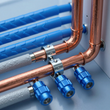Tuberías de cobre con válvulas azules y tubos aislados en una instalación de fontanería.