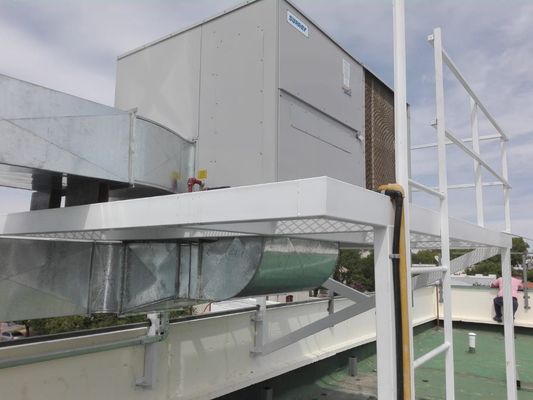 Equipos de climatización y conductos en la azotea junto a un edificio bajo un cielo nublado.