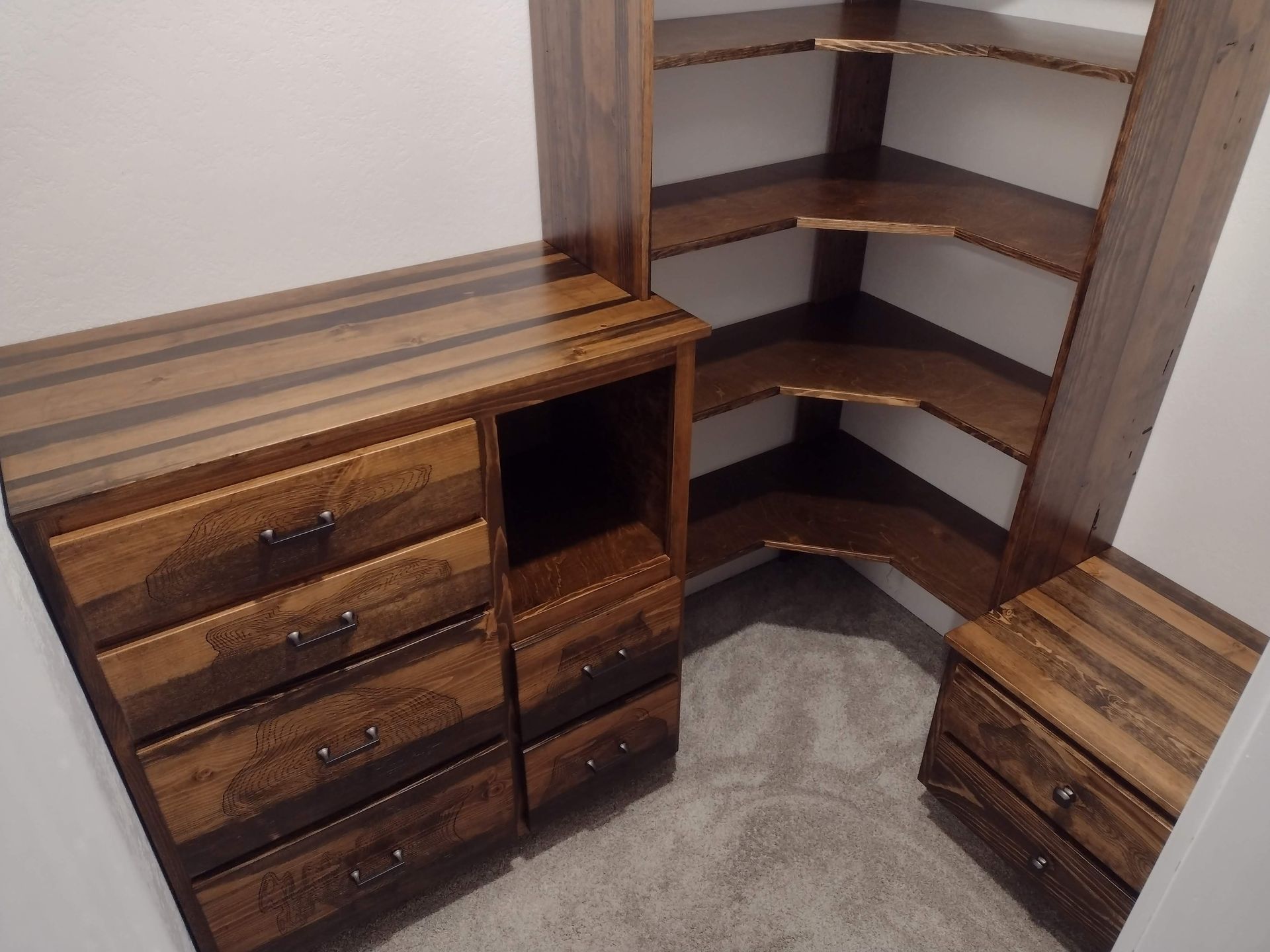 A corner of a closet with wooden shelves and drawers