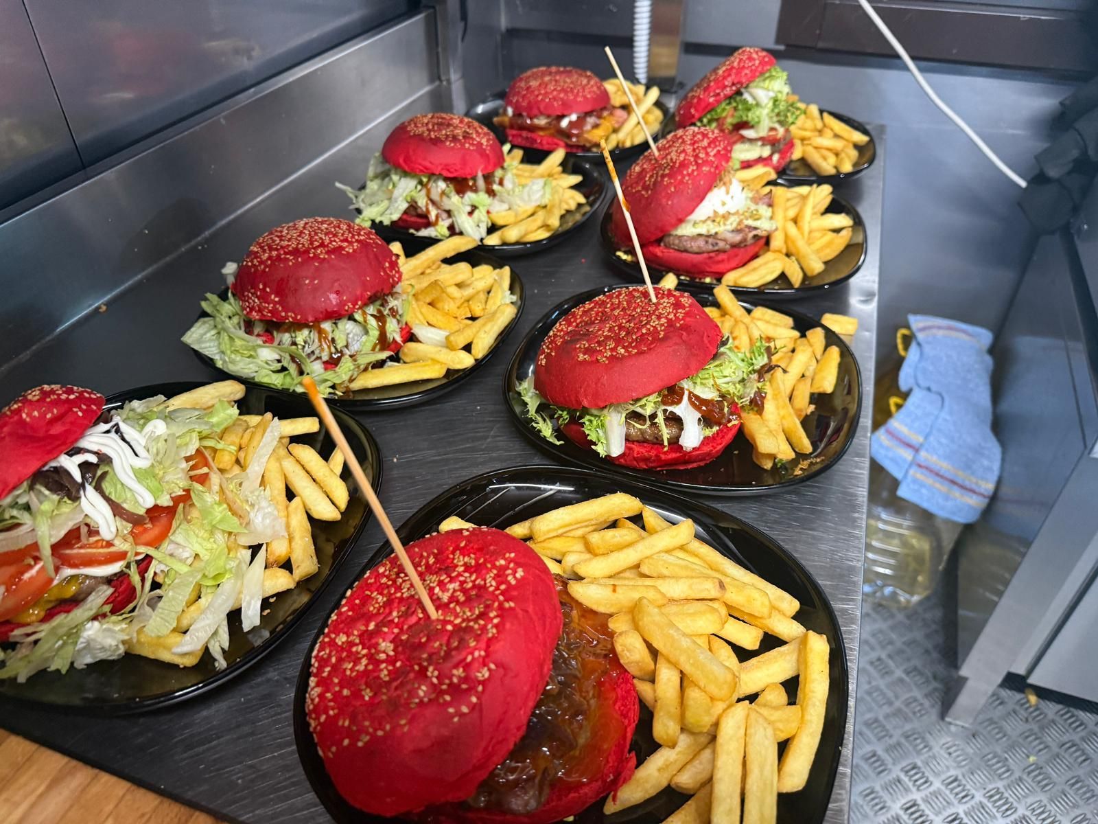 Hot dog e anelli di cipolla su un tavolo con vari condimenti e salse.