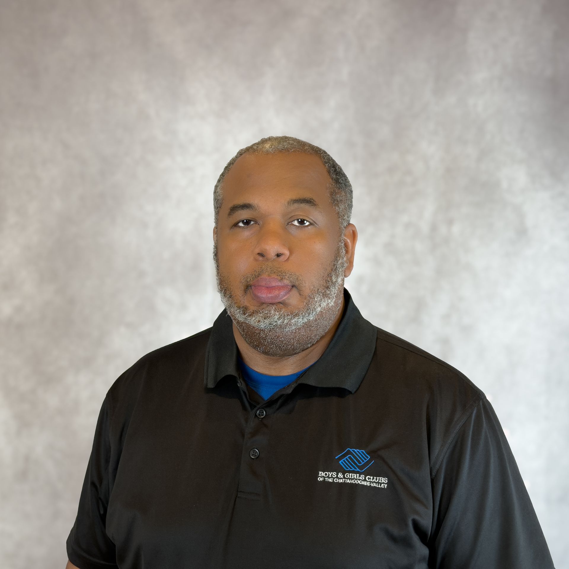 Portrait of a man in a black polo shirt against a gray backdrop