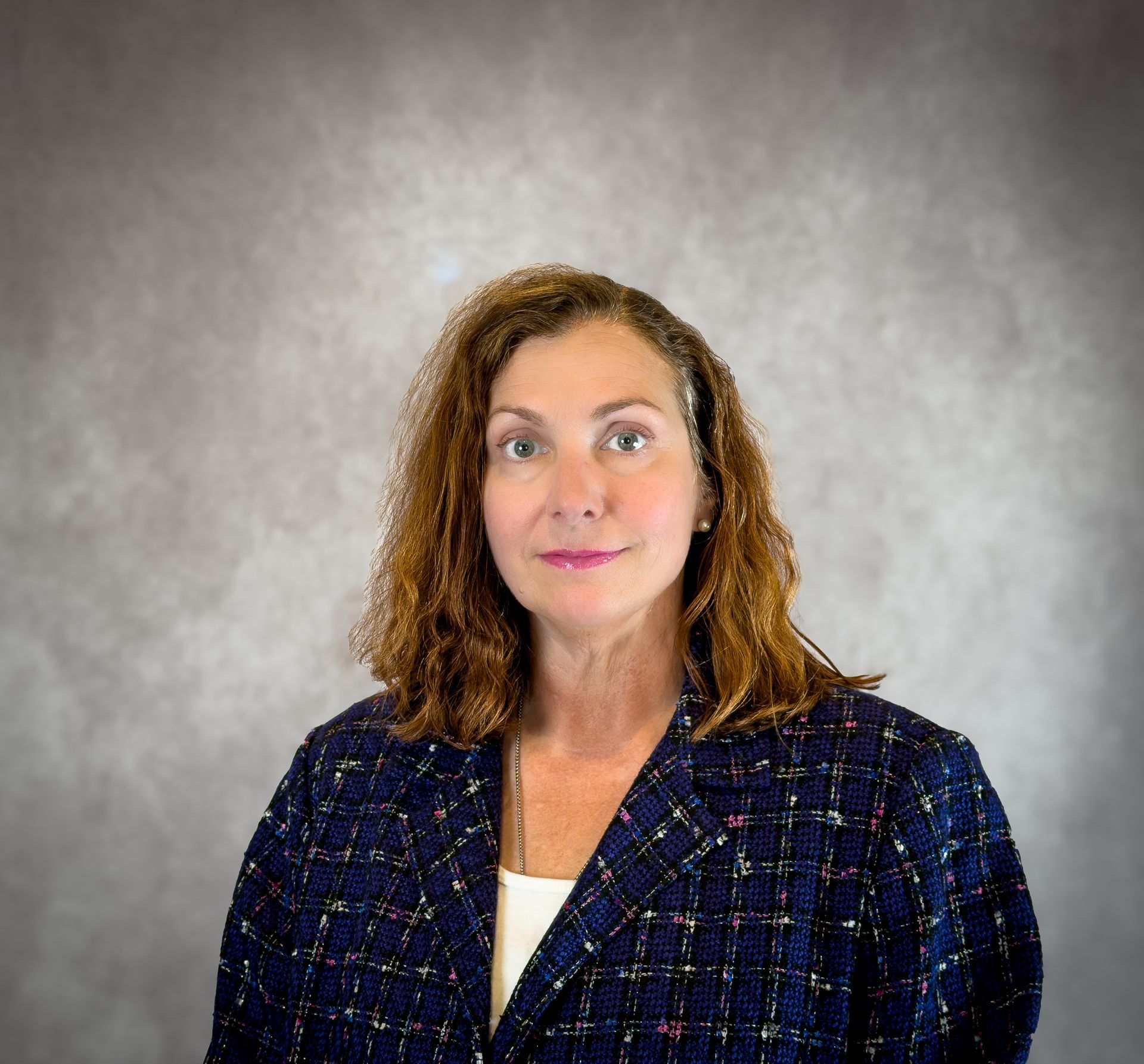 Portrait of a woman in a navy blazer against a gray backdrop
