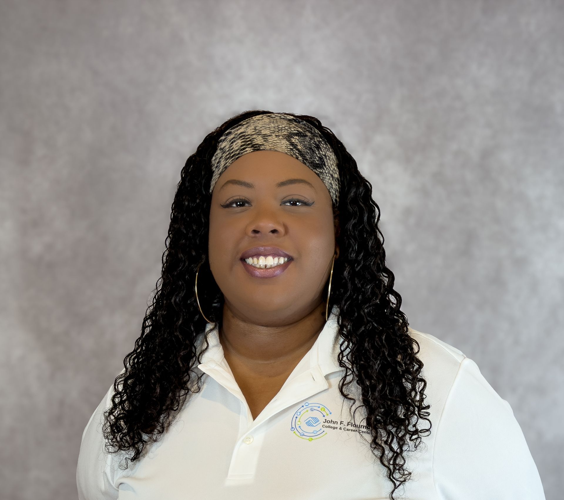 Woman smiling in a white collared shirt against a gray studio backdrop