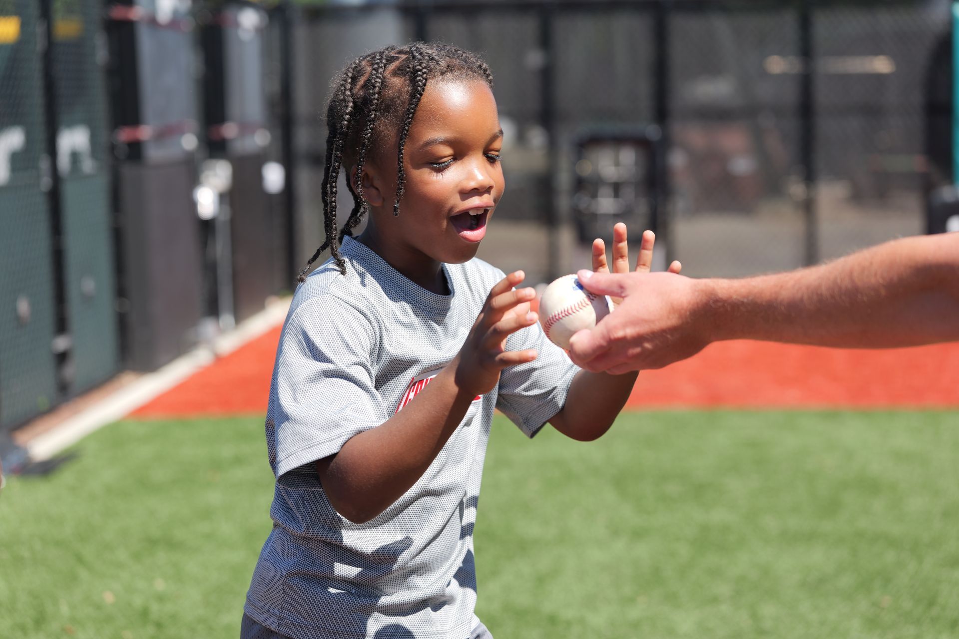 Child reaching for a ball during an outdoor sports activity on a green turf field