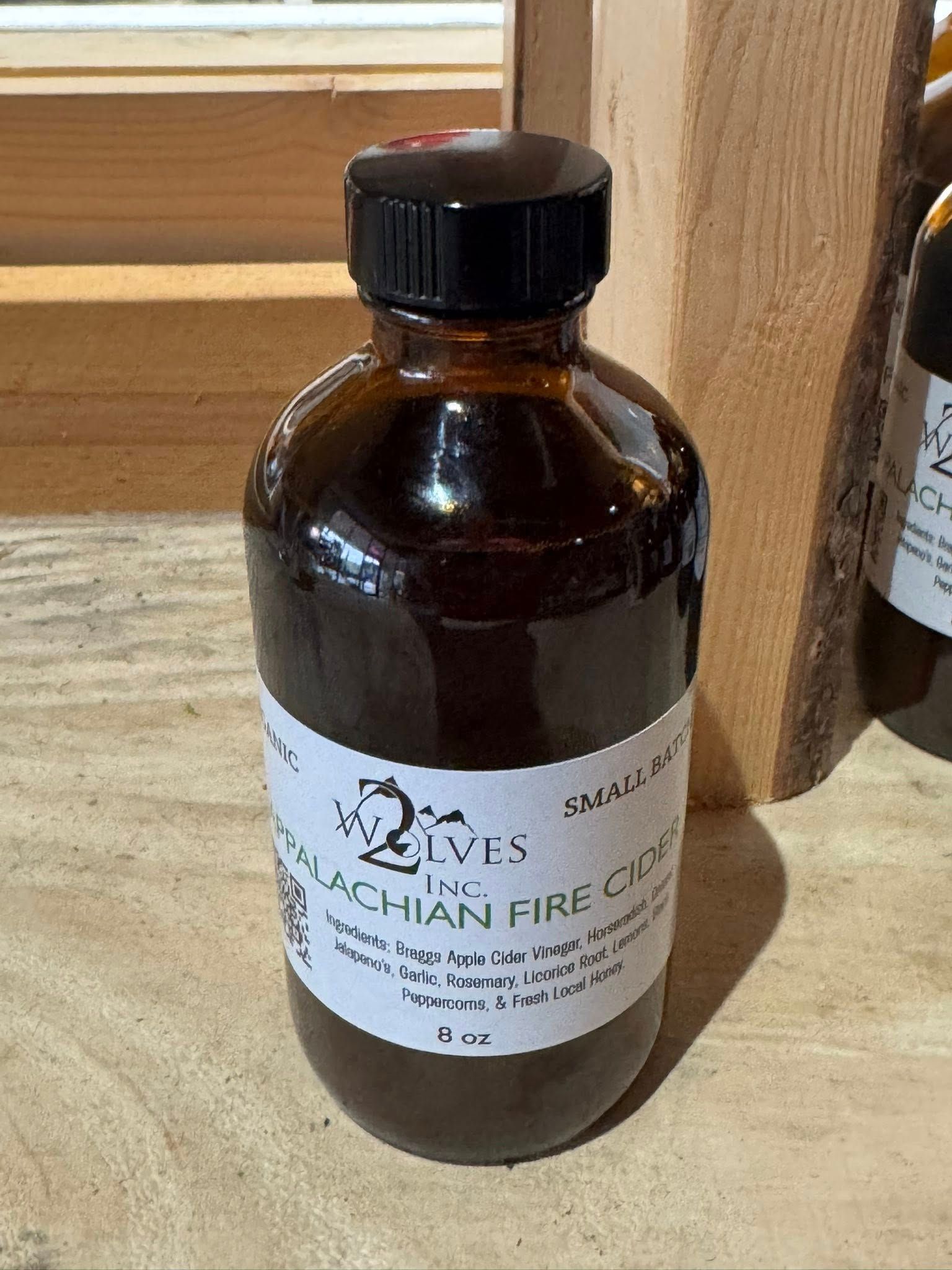 Amber glass bottle with black cap and white label on a wooden shelf.