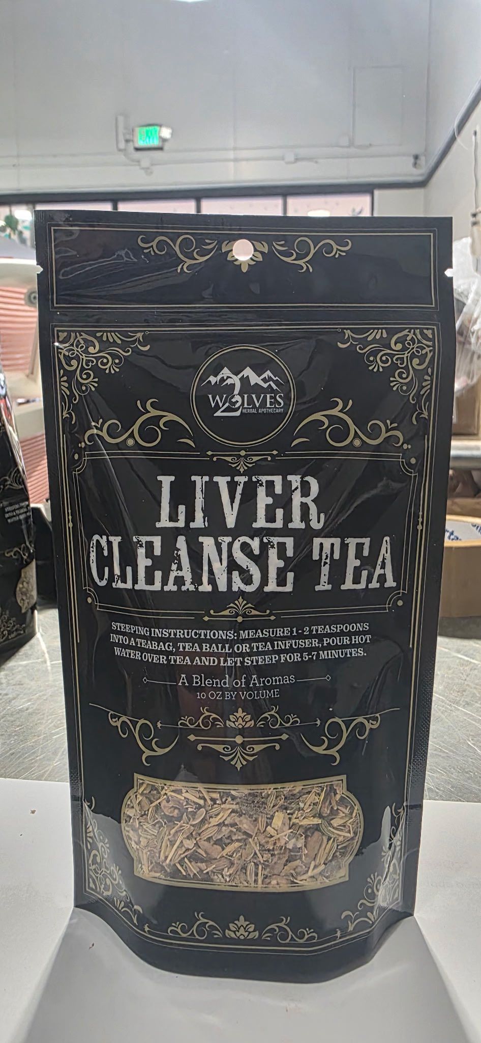 Black stand-up pouch labeled LIVER CLEANSE TEA on a store counter.