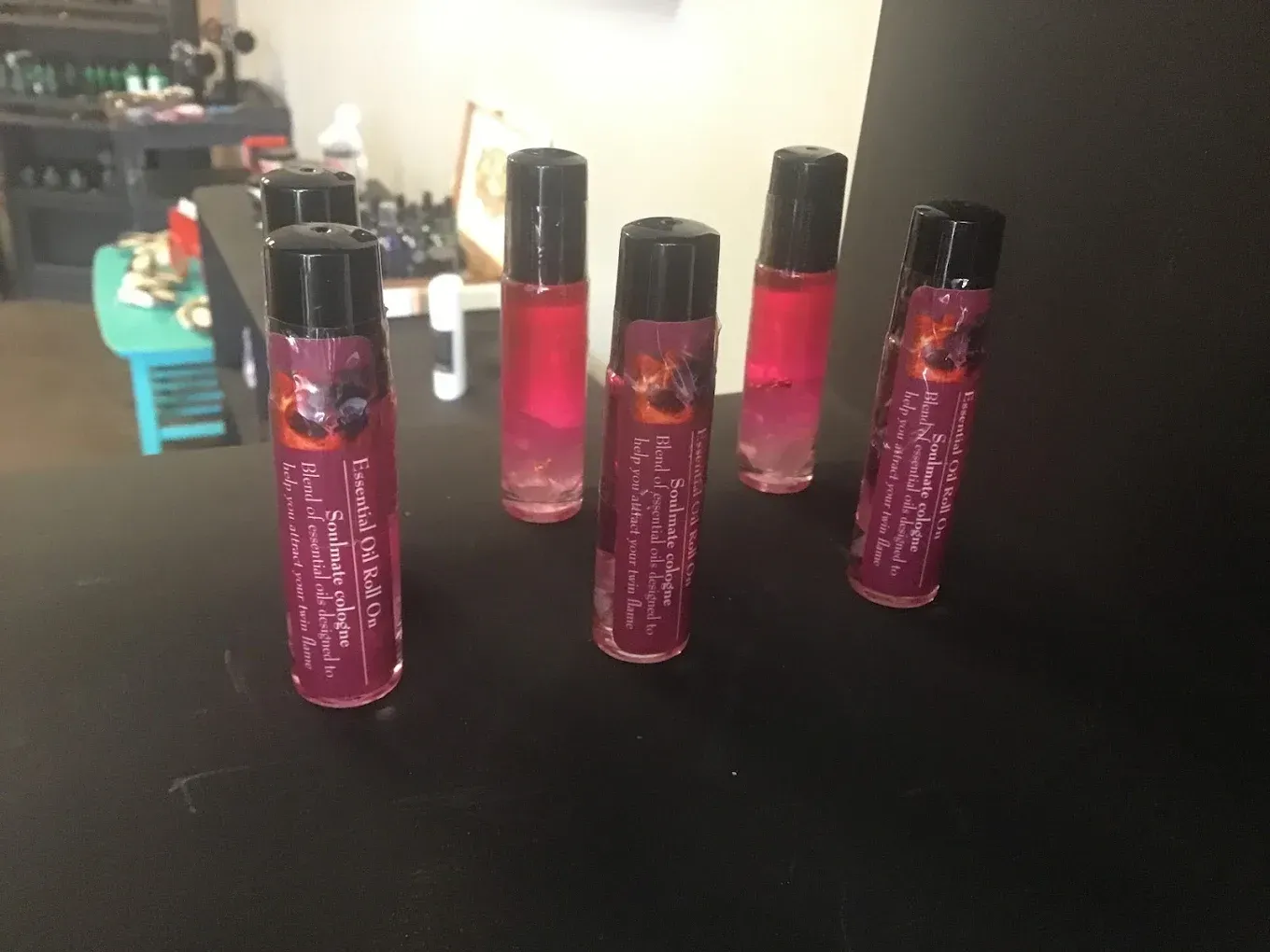 Five pink glitter lip gloss tubes with black caps arranged on a table.