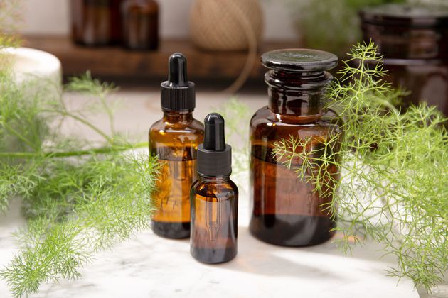 W2Vives Inc. tattoo oil jars and a green skull-shaped bottle on a wooden shelf with plants