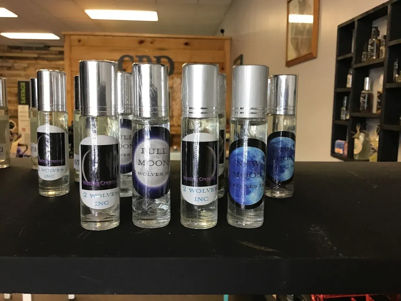 Rows of small clear bottles with silver caps on a black counter in a store or showroom.