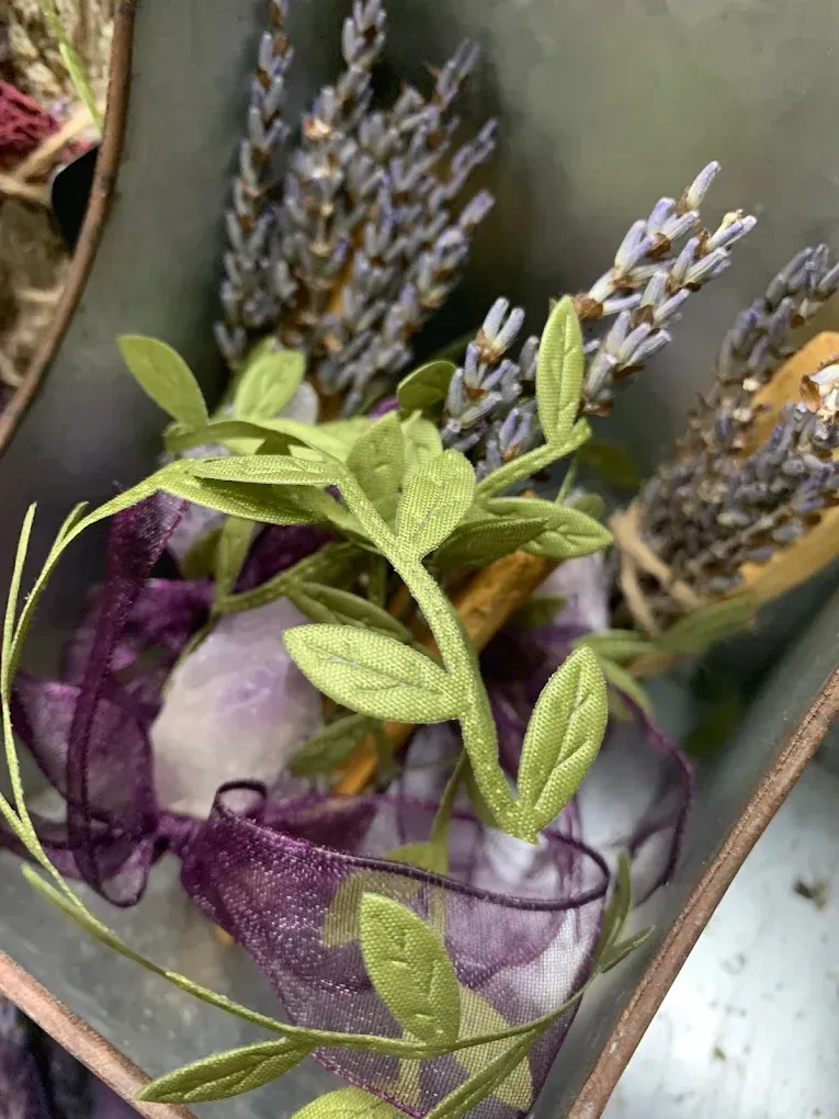 Lavender sprigs and green herb stems wrapped in purple ribbon in a rustic wooden box