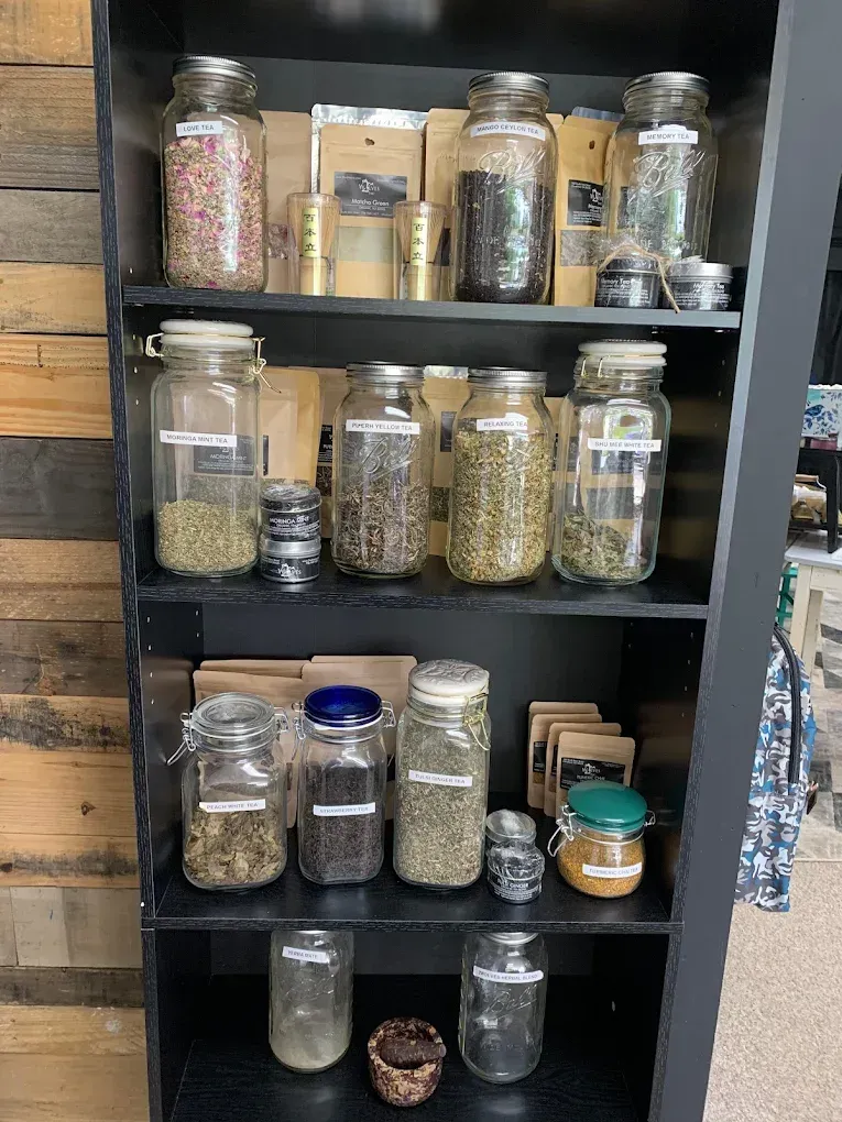 Black shelving unit filled with glass jars of dry goods and spices in a pantry or kitchen.
