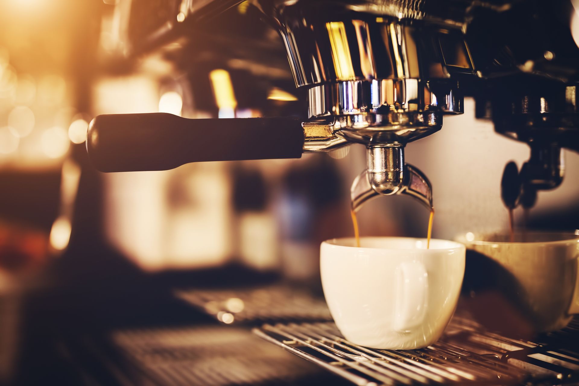 Espresso machine brewing coffee into a white cup, cafe setting.